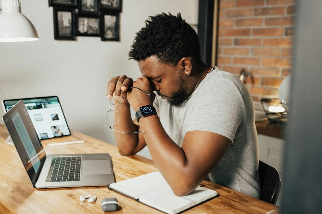 A Tired Graduate Sitting in front of His Laptop Rubbing His Eyes After A Long Day Searching For a Job